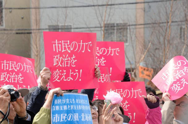 集まった市民が共通ポスターを掲げて応援