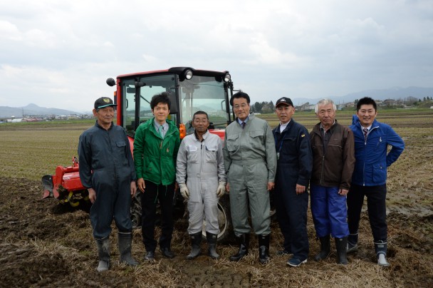 岡田代表が田おこし体験後に農家の方々と。（右端が松浦氏、左から２番目が緑川氏）